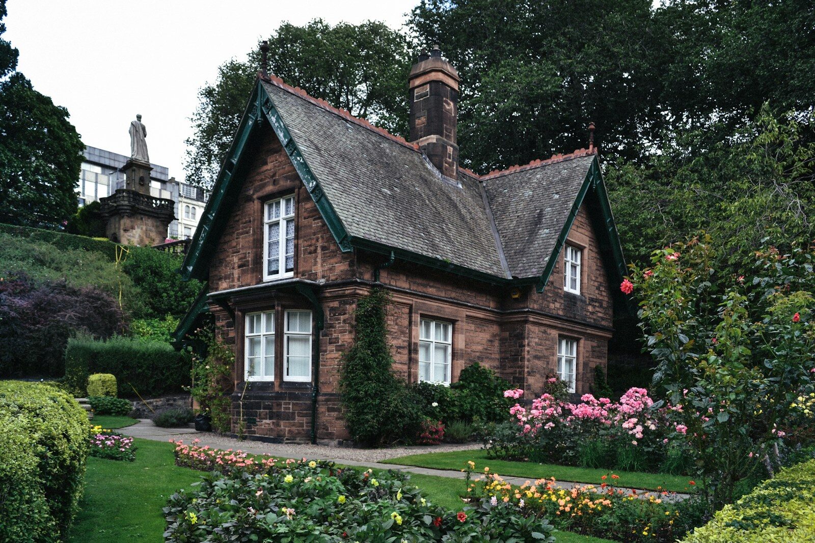 A stone cottage with a slate roof surrounded by a lush garden in Edinburgh